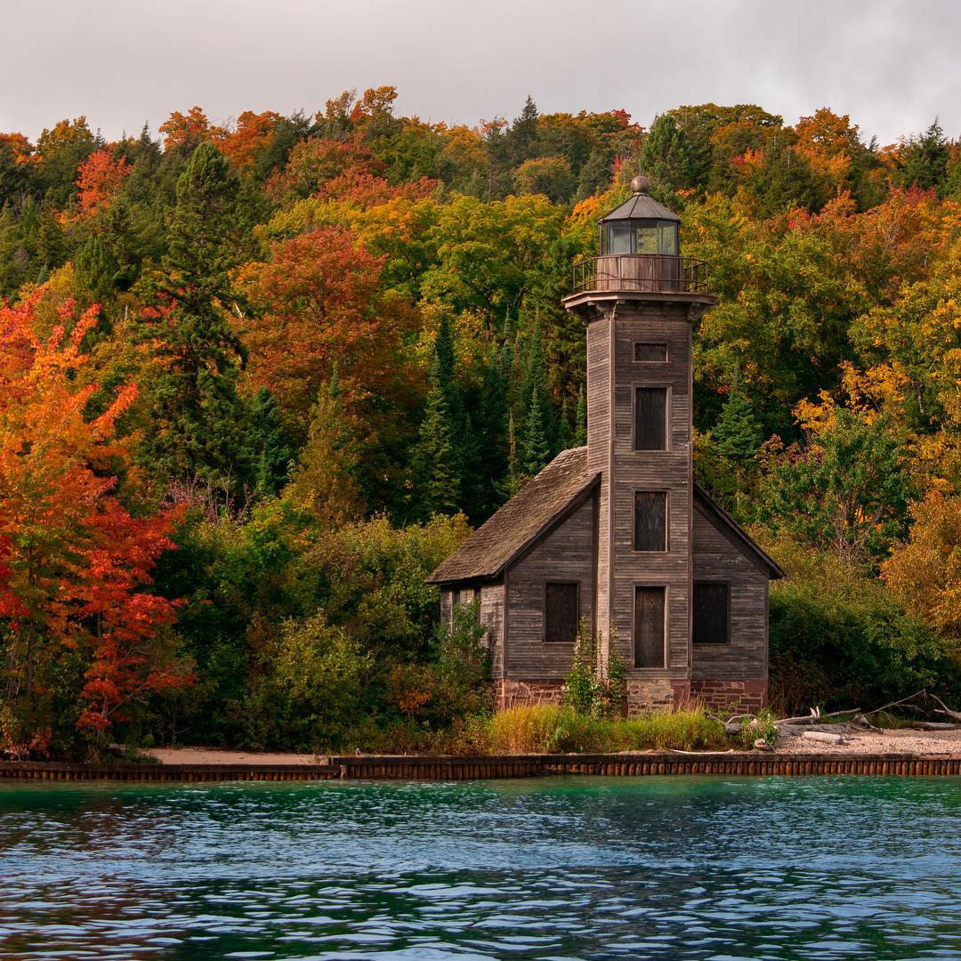 View of East Channel Lighthouse from a Pictured Rocks Cruise with fall foliage in the background. PC: @colerobertfisher